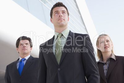 Three businesspeople standing outdoors by building