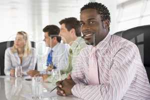 Four businesspeople in a boardroom smiling