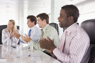 Four businesspeople in a boardroom applauding
