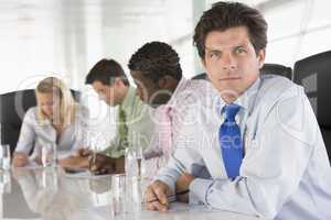 Four businesspeople in a boardroom writing