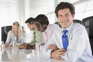 Four businesspeople in a boardroom smiling