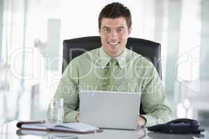 Businessman sitting in office with personal organizer using lapt