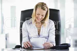 Businesswoman in office looking at personal organizer smiling