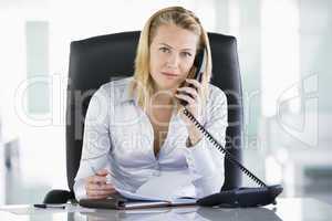 Businesswoman in office with personal organizer open on telephon