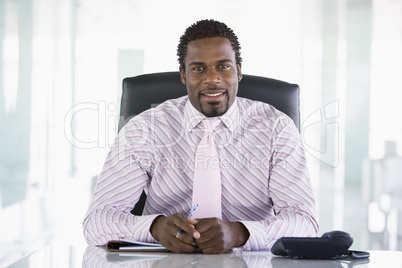 Businessman sitting in office with personal organizer smiling