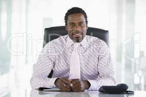 Businessman sitting in office with personal organizer smiling