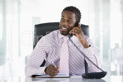 Businessman sitting in office with personal organizer open on te