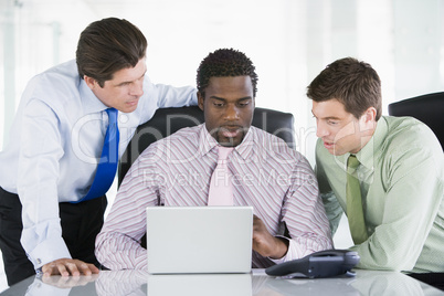 Three businessmen in a boardroom looking at laptop