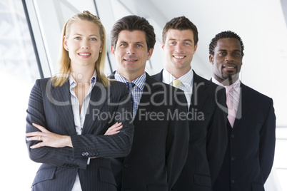 Four businesspeople standing in corridor smiling