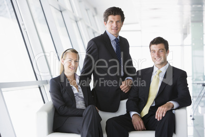 Three businesspeople sitting in office lobby smiling