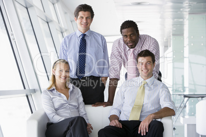 Four businesspeople in office lobby smiling