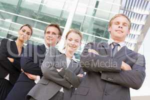 Four businesspeople standing outdoors smiling