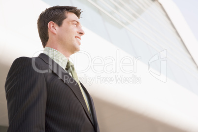 Businessman standing outdoors by building smiling