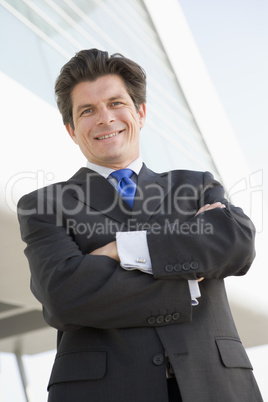 Businessman standing outdoors by building smiling