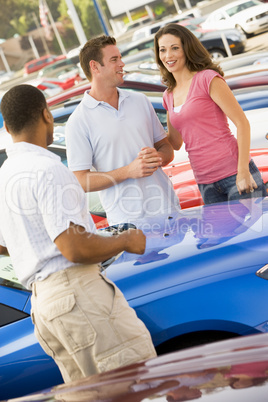 Couple discussing new car with salesman