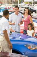 Family discussing new car with salesman