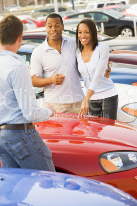 Young couple discussing new car with salesman