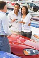 Couple picking up new car from salesman