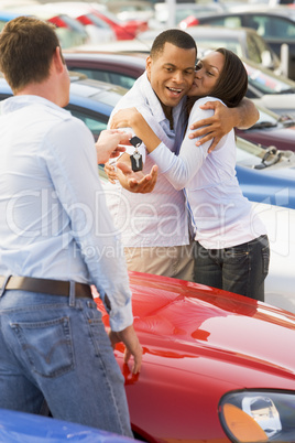Couple collecting new car from salesman
