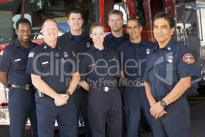 Portrait of firefighters standing by a fire engine