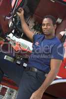 A firefighter standing by the cab of a fire engine