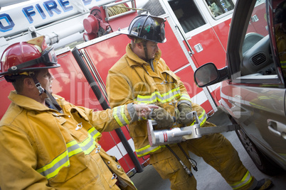 Firefighters cutting open a car to help an injured person