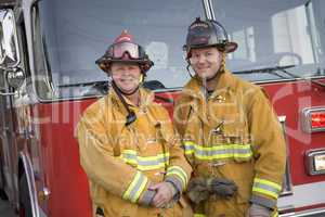 Portrait of two firefighters by a fire engine