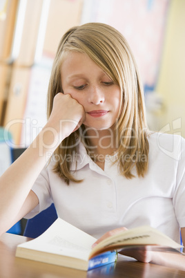 Schoolgirl reading a book in class