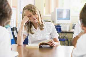 Schoolgirl reading a book in class