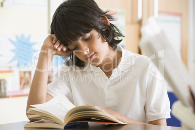 Schoolboy reading a book in class