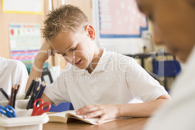 Schoolboy reading a book in class