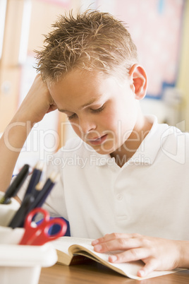 Schoolboy reading a book in class