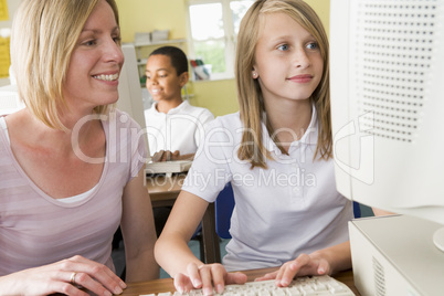 Teacher and schoolgirl studying in front of a school computer