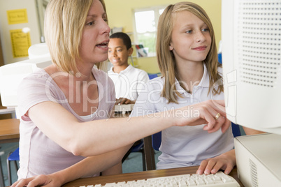 Teacher and schoolgirl studying in front of a school computer