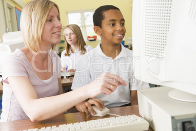 Teacher and schoolboy studying in front of a school computer