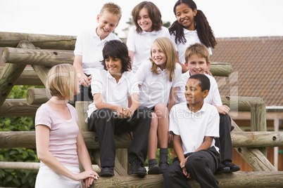 School children sitting on benches outside with their teacher