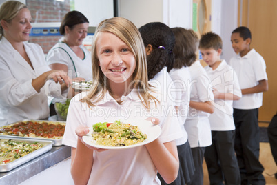 Schoolgirl holding plate of lunch in school cafeteria