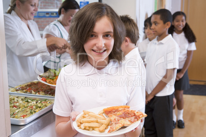 Schoolgirl holding plate of lunch in school cafeteria