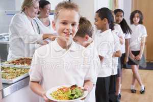Schoolboy holding plate of lunch in school cafeteria