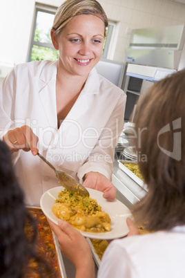 Lunchlady serving plate of lunch in school cafeteria