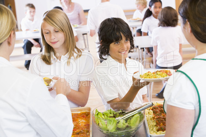 Lunchladies serving plates of lunch in school cafeteria