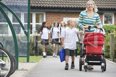 A woman with a pushchair walking her son home from school
