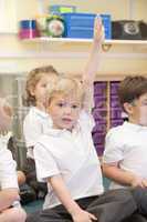 A schoolboy raises his hand in a primary class