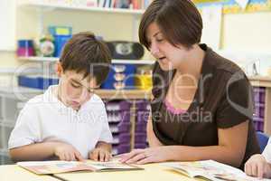 A schoolboy and his teacher reading in a primary class