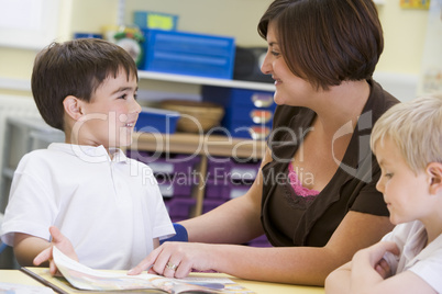 A schoolboy and his teacher reading in a primary class