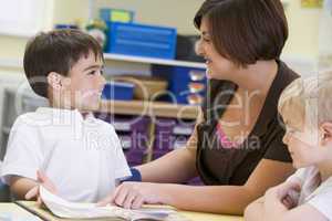 A schoolboy and his teacher reading in a primary class