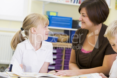 A schoolgirl and her teacher reading in a primary class
