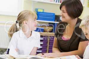 A schoolgirl and her teacher reading in a primary class