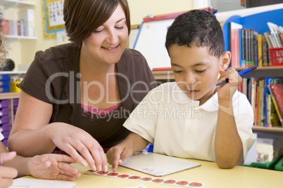 Primary school teacher helping boy learn numbers