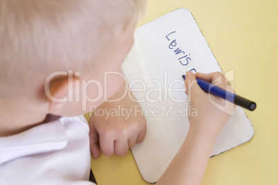 Boy learning to write name in primary class